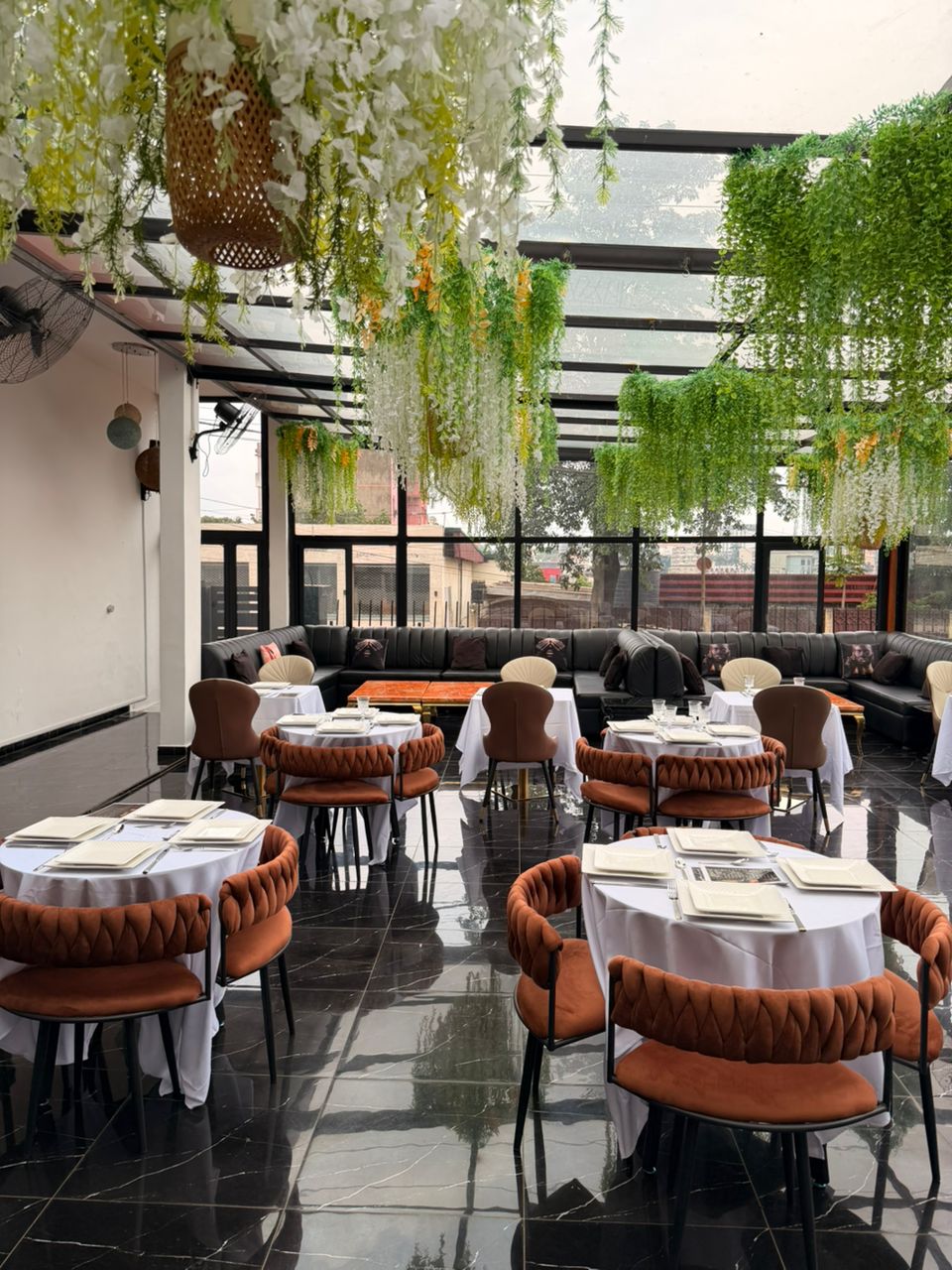 Terrasse-restaurant élégante dressée sous une verrière végétalisée